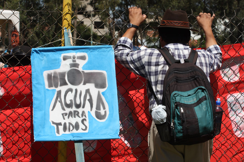 Bolivian man standing in front of a fence with protests signs.